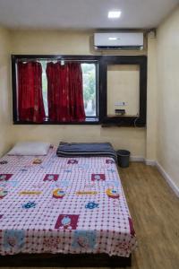 a bedroom with a bed and a window with red curtains at Hotel Shree in Indore