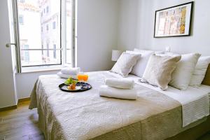 a white bed with a tray of food on it at Stradun Main Street Residence in Dubrovnik