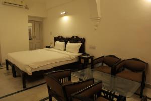 a bedroom with a bed and two chairs and a glass table at Chirmi Palace - A Heritage Home in Jaipur