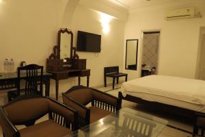 a bedroom with a bed and a desk and a mirror at Chirmi Palace - A Heritage Home in Jaipur