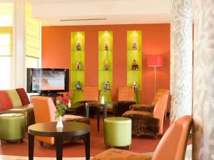 a living room with orange and green furniture and a tv at Ibis Cotonou in Cotonou