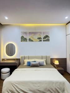 a bedroom with a large white bed and some paintings at AnChi Homestay in Hòa Bình