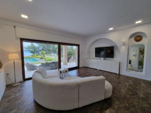 a living room with a white couch and a tv at Villa Musa with private pool in Afitos