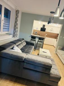 a living room with a black couch and a kitchen at AS Apartment Free Parking and Peaceful Nature near Ljubljana in Škofljica