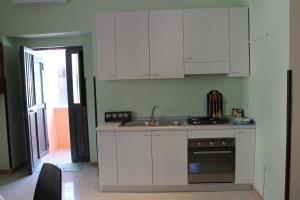 una cucina con armadi bianchi, lavandino e piano cottura di AnVi Apartment a Pollena Trocchia