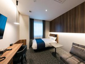 ein Hotelzimmer mit Bett und Schreibtisch in der Unterkunft THE STILL HOTEL - Opening April 3, 2026 in Ozu