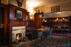 a fireplace in a restaurant with a table and chairs at Arbutus Hotel in Killarney