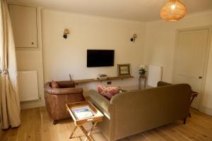 a living room with a couch and a television at Great Ashley Farm Holiday Cottage & Shepherds Huts in Bradford on Avon