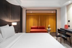 a hotel room with a bed and a red chair at CMYK Boutique Hotel in Bangkok