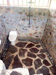 a bathroom with a stone wall and a toilet at Cozy cove hut in Pulau Sarang