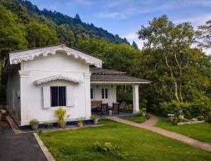 a small white house in the middle of a yard at Hill House Haldummulla in Badulla