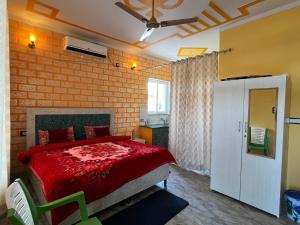 a bedroom with a red bed and a brick wall at Bhadraj Valley Homestay in Dehradun