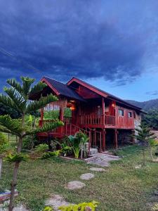 a wooden house with a palm tree in front of it at Cozy cove hut in Pulau Sarang