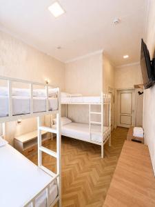 a room with three bunk beds and a flat screen tv at Hostel DANEXAN APA in Nukus