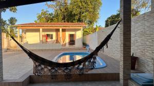 a hammock in front of a house with a pool at Casa de veraneio jacuma in Conde