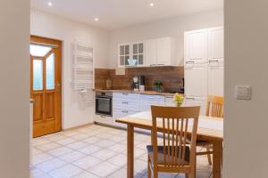 a kitchen with white cabinets and a wooden table and chairs at Landhaus Bender Ferienwohnung mit Terrasse und Garten in Straden