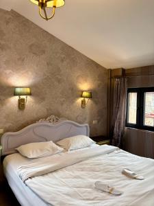a bedroom with a large white bed with two slippers on it at 34 Silver Rooms in Tbilisi City