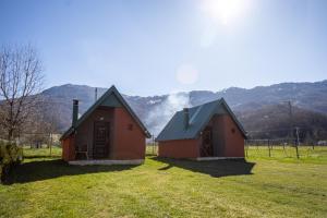 two small buildings in a field with mountains in the background at Rest&peace homes in Mojkovac