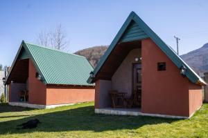 a small house with a green roof and a cat in front at Rest&peace homes in Mojkovac