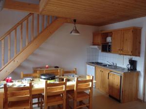 a kitchen with a wooden table and chairs and a staircase at Goélia - Les Chalets des Marmottes in Saint-Jean-dʼArves