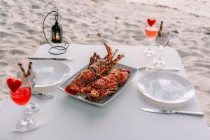 a table with a plate of seafood and two wine glasses at Crystal sea inn in Bileffahi