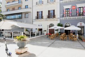 a patio with tables and umbrellas in front of a building at barneys design apartment in Taranto