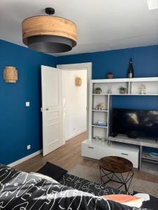 a living room with blue walls and a flat screen tv at Le Grand Bleu in Troyes
