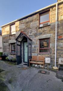 a wooden bench sitting outside of a stone building at Penbryn Holidays No 2 in Barmouth