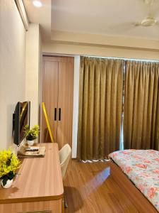 a bedroom with a bed and a desk and a television at Luxury stays in Greater Noida