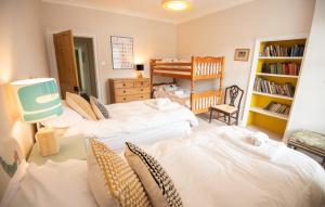 a bedroom with two beds and a crib in it at Old Vicarage Mortehoe Near Woolacombe 2 x sleeps 4 and 1 x sleeps 10 cottages in Mortehoe