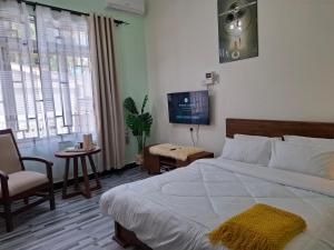 a bedroom with a bed and a chair and a tv at G4 homez in Morogoro