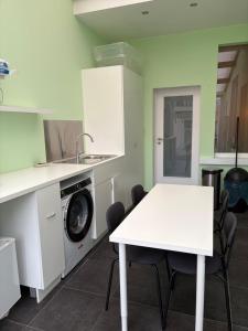 a kitchen with a white table and a washing machine at Hébergement proche de Atomium Expo Serres Royales in Grimbergen
