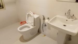 a white bathroom with a toilet and a sink at Hotel DR Retreat in Pakhyong