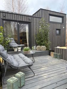 a wooden deck with a chaise lounge and a house at ToTu Tiny House Sauna & wanna ogrodowa in Dobiesz