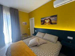 a bedroom with a bed with a yellow wall at HOUSE on sunday SOLE in Crotone