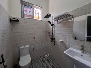 a bathroom with a toilet and a sink and a window at G4 homez in Morogoro