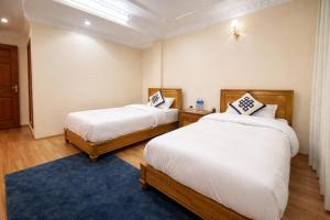 a bedroom with two beds and a blue rug at Monastery View Homestay in Kathmandu