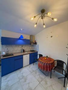 a kitchen with blue cabinets and a table and a ceiling fan at ksenia apartment in Borjomi