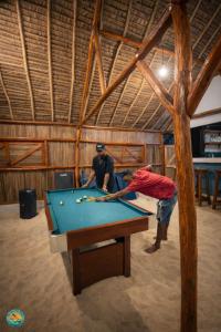 two men playing pool on a pool table at Ny Fano Kite Lodge in Ivovona