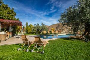two chairs sitting in the grass near a swimming pool at La Almunia del Valle in Monachil