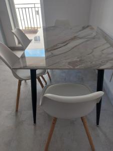 a marble table with two white chairs and a glass table at Romanescu Parc Apartment in Craiova +1 photo