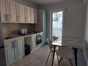 a kitchen with white cabinets and a table and chairs at Romanescu Parc Apartment in Craiova