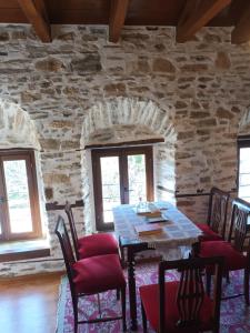 a dining room with a table and chairs and a stone wall at Archontiko Michael Pelion in Vyzitsa