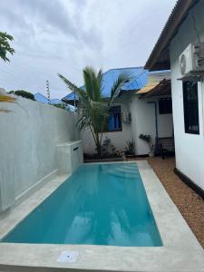 a small blue swimming pool in front of a house at Sisters House in Pingwe