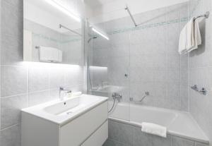 a white bathroom with a sink and a bath tub at Hotel Atlantico self check-in in Lugano +31 photos