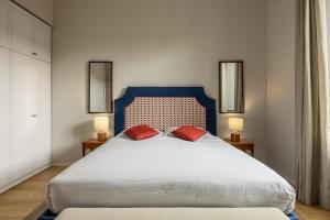 a bedroom with a large bed with two red pillows at Brunelleschi Prestige by MMega in Florence