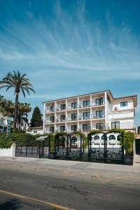 a white building with a fence and a palm tree at Arcos de Montemar in Torremolinos
