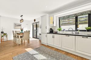 a kitchen with white cabinets and a dining room with a table at Cnoc Na RI in Strandhill