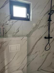 a bathroom with a shower with a white marble wall at Villa Violand 2 in Limanu