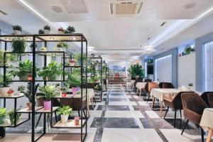 ein Restaurant mit Tischen, Stühlen und Topfpflanzen in der Unterkunft Fergana hotel in Fargʻona